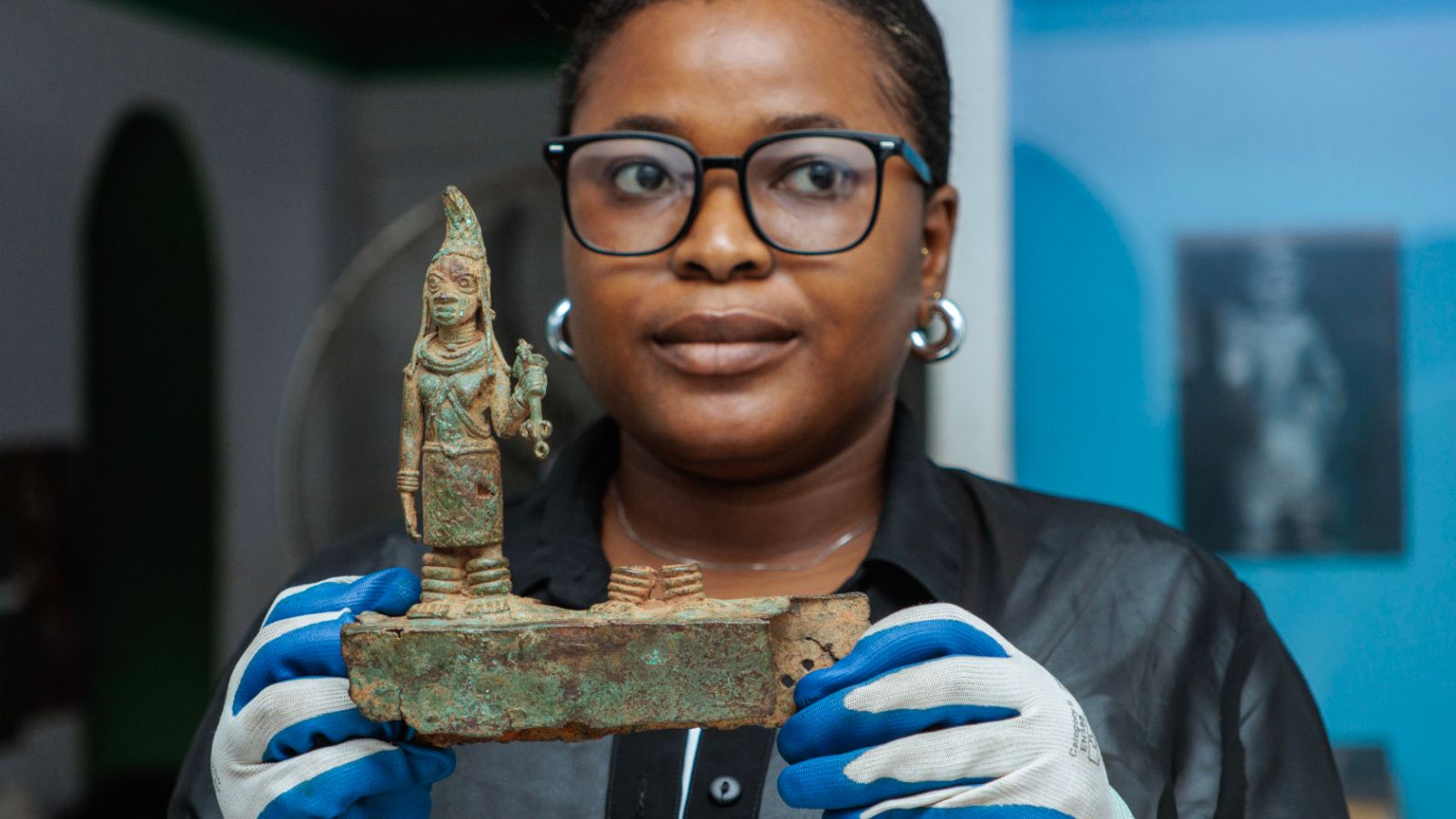 Kuratorin Oluchi Anyiam hält das Fragment eines Altartableaus in den Händen: die verehrte Iy’Ọba (Königinmutter) auf diesem Fragment ist an ihrer hohen, nach vorne geneigten Frisur zu erkennen, die mit einem Korallennetz bedeckt ist.